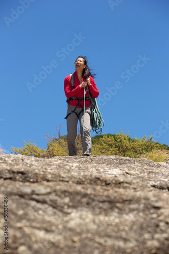 asian female climber carrying rope on mountain