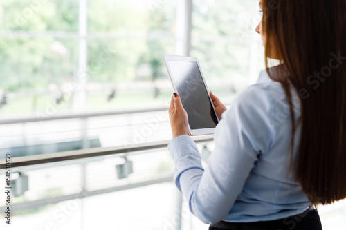 Hands of business woman touching her tablet in modern interior