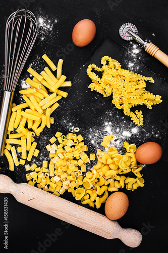 egg pasta various format with kitchen utensil over slate photo