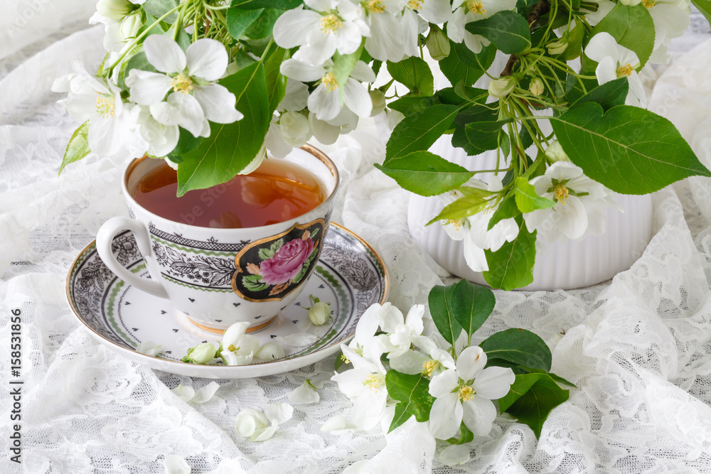 Cup of tea on wooden table and apple blossom. Tea time concept. Breakfast tea cup served with flowers. Cup of tea on wooden table and apple blossom. Tea time concept. Breakfast tea cup served with flowers.