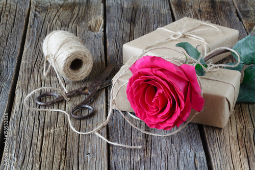 Red roses and gift box on a wooden background