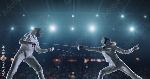 4K video in slow motion of two female fencing athletes. The action takes place on professional sports arena with spectators and lense-flares. Women wear unbranded sports clothes. Arena is made in 3D. photo