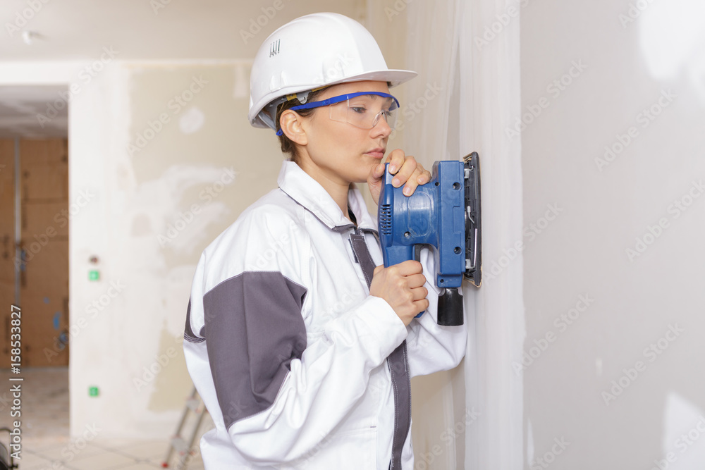 female construction worker smoothing wall surface female construction worker smoothing wall surface