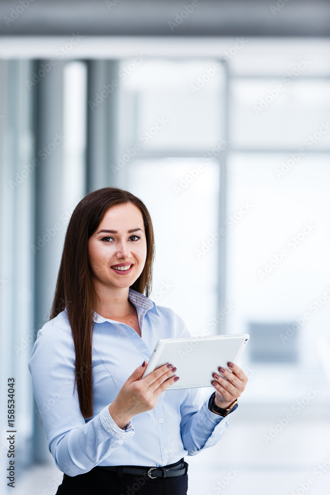 Attractive business woman standing with tablet in her hands and smiling Attractive business woman standing with tablet in her hands and smiling