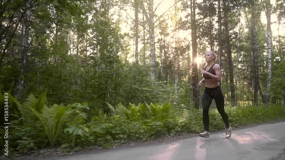 Muscular girl on a running exercise. Beautiful young athlete engaged in sports running in summer forest. slow motion Muscular girl on a running exercise. Beautiful young athlete engaged in sports running in summer forest. slow motion