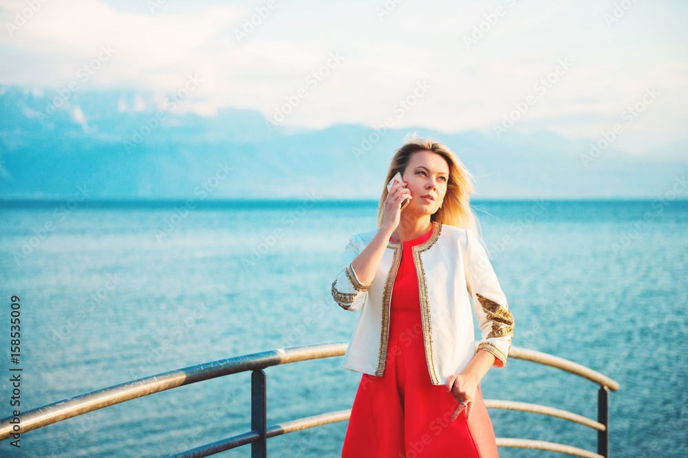 Outdoor portrait of laughing beautiful blond woman talking on the phone
