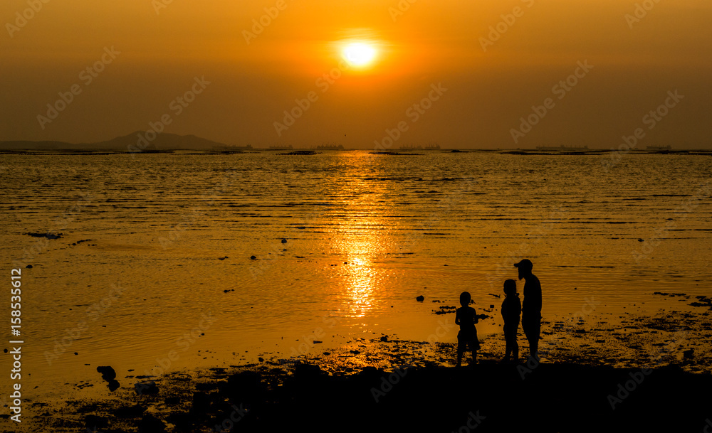 Silhouette of family at sea with sunset sky