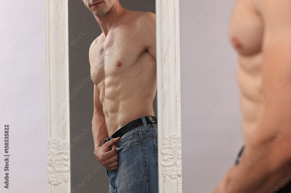 Φωτογραφία Attractive muscular man admiring his muscles in mirror