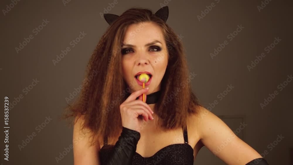 Attractive woman in black clothes sucks lollypop with her eyes closed and then opens her eyes looking at camera. Attractive woman in black clothes sucks lollypop with her eyes closed and then opens her eyes looking at camera.