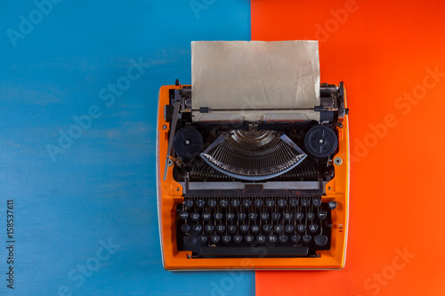 Workspace with orange vintage typewriter on blue and orange background