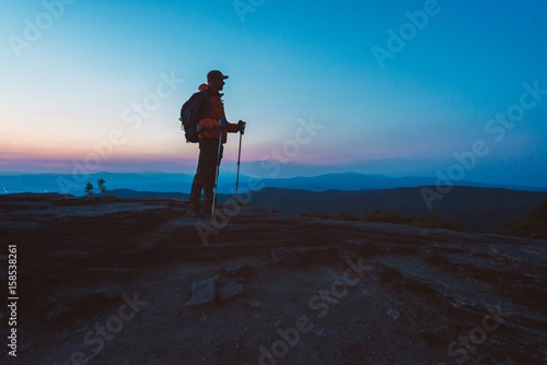 Man tourist with trekking on top of hill