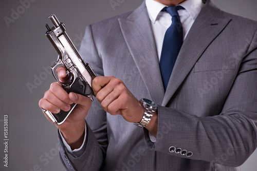 Businessman pulling the gun out of pocket