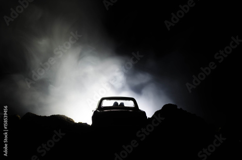 silhouette of car with couple inside on dark background with lights and smoke. Romantic scene. Love concept