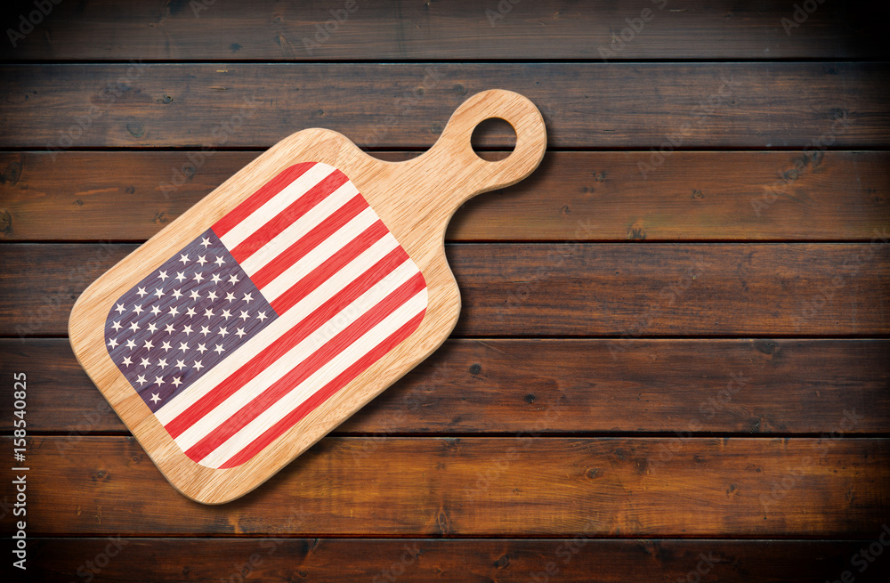 Naklejka premium Concept of American cuisine. Cutting board with a American flag on a wooden background