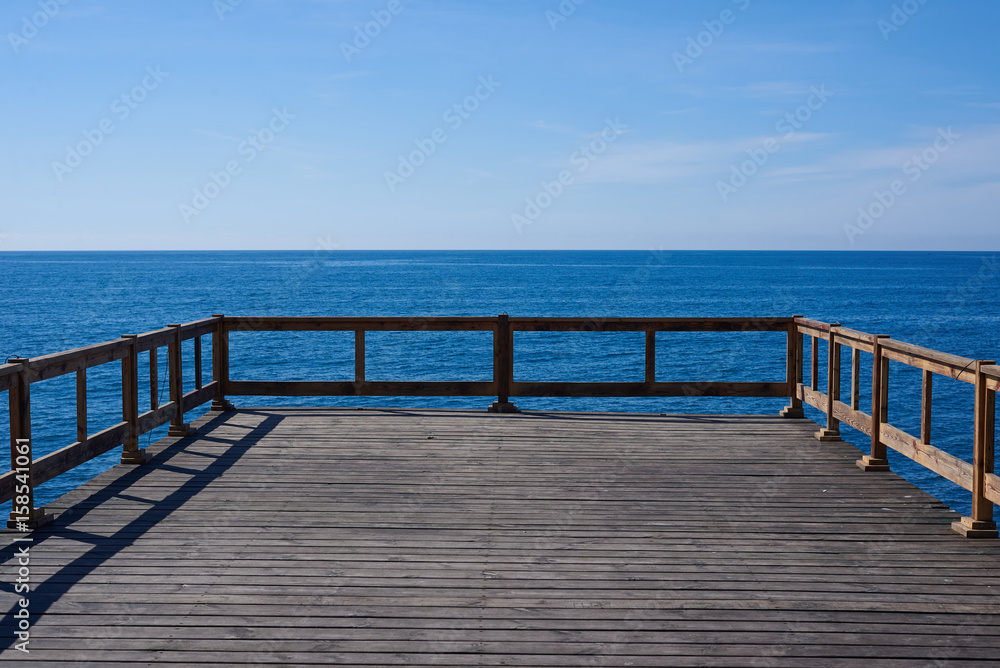 Wooden pier in blue ocean with horizon background. Place for advertising travel, fishing, diving, shipping products. Perfect field with sea, free sky, fresh air.