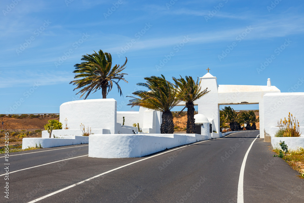 road with white entry gate and palm trees, Lanzarote Spain