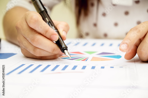 Business woman working with new startup project.Hand woman holding pen pointing on summary report chart and calculate finance.discussion and analysis data the charts and graphs.