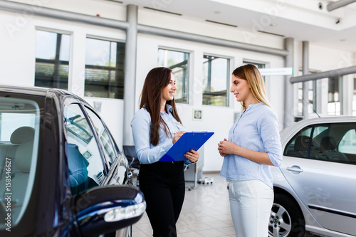 Two women makeing a agreement in modern car dealership