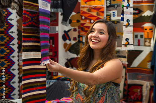 Close up of a young woman touching an andean backpack traditional clothing textile yarn and woven by hand in wool, colorful fabrics background photo