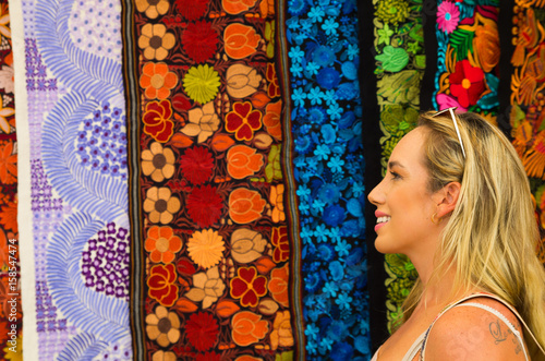 Close up of a beautiful blonde young woman looking andean traditional clothing, colorful fabrics background