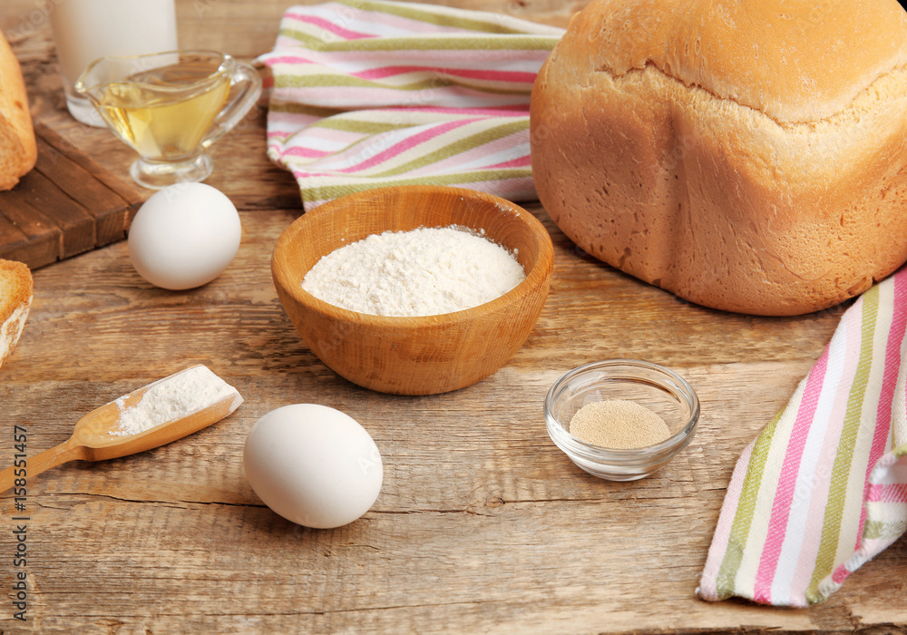Ingredients for preparing bread in machine on wooden table Ingredients for preparing bread in machine on wooden table