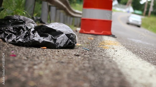 Garbage bag and dirty ugly litter on the side of a windy road 