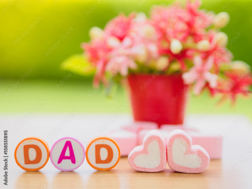 Obraz premium Father's day concept. DAD alphabet with marshmallow in the shape of heart and flower on background