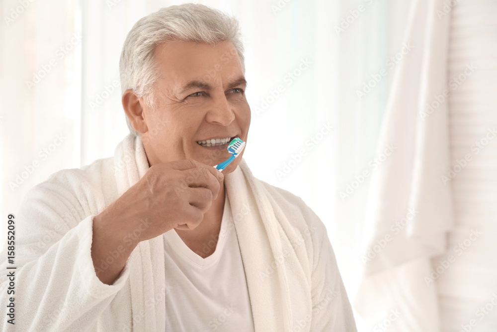 Senior man cleaning teeth at home Senior man cleaning teeth at home