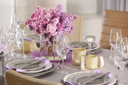 Beautiful table setting with silver cutlery and lilac bouquet