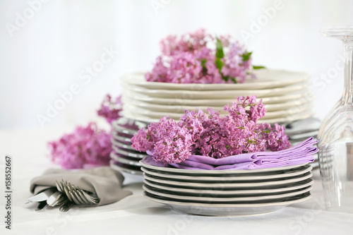 Pile of dishware and lilac blossom on table