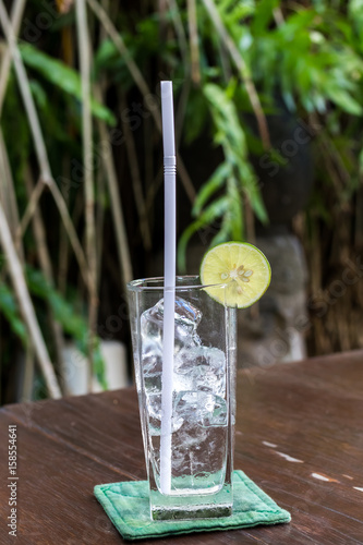 Glass with ice cubes and lime on a tropical background. Bali island.