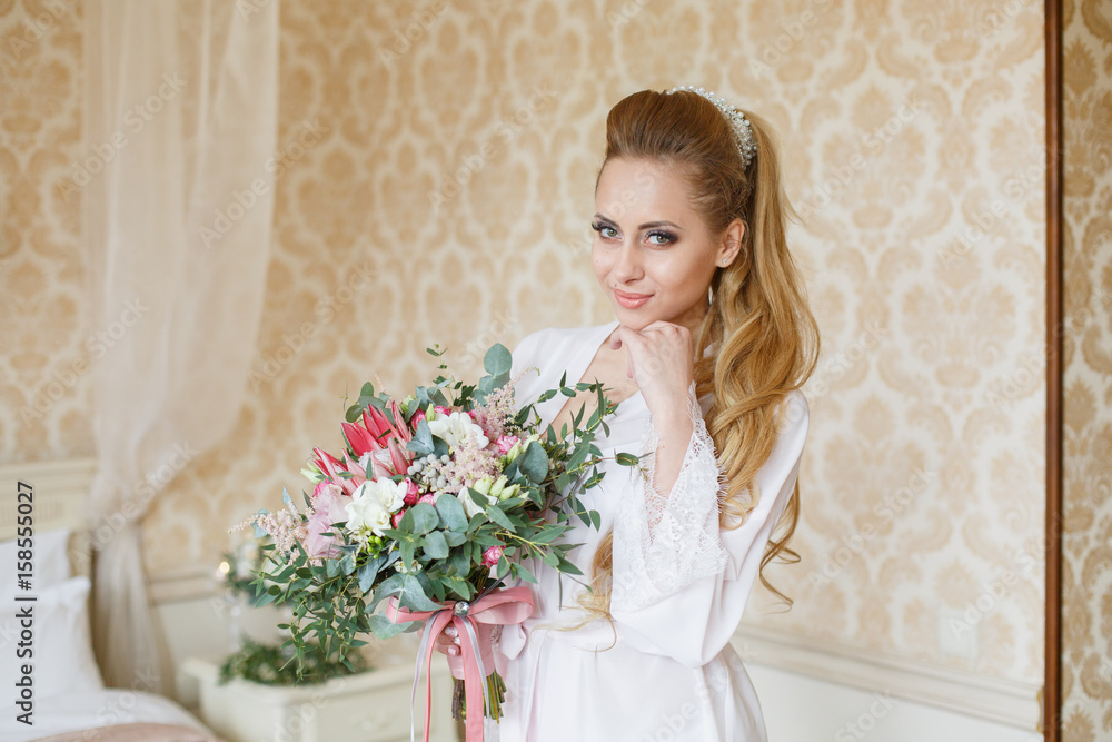 Pretty young girl. Blonde woman with luxurious long hair tail. Boudoir morning of the bride. Taking wedding bouquet in her hands Pretty young girl. Blonde woman with luxurious long hair tail. Boudoir morning of the bride. Taking wedding bouquet in her hands