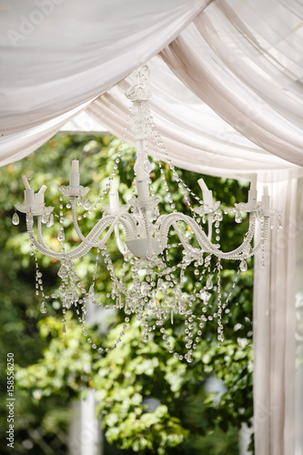 Outdoor scene with chandelier  overgrown with greenery. Rustic style. 