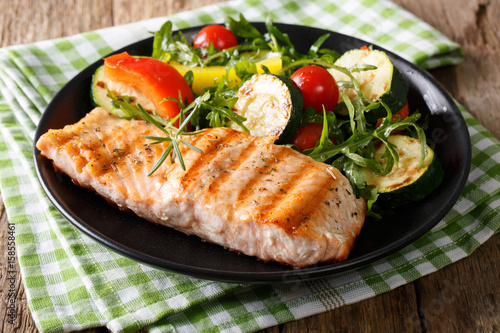 grilled salmon fillet with salad of zucchini, arugula, pepper and tomatoes close-up. horizontal
