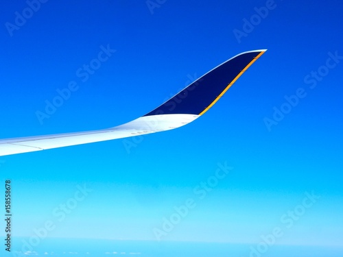 Aircraft wing on flight to travel in the atmosphere with navy blue sky background.