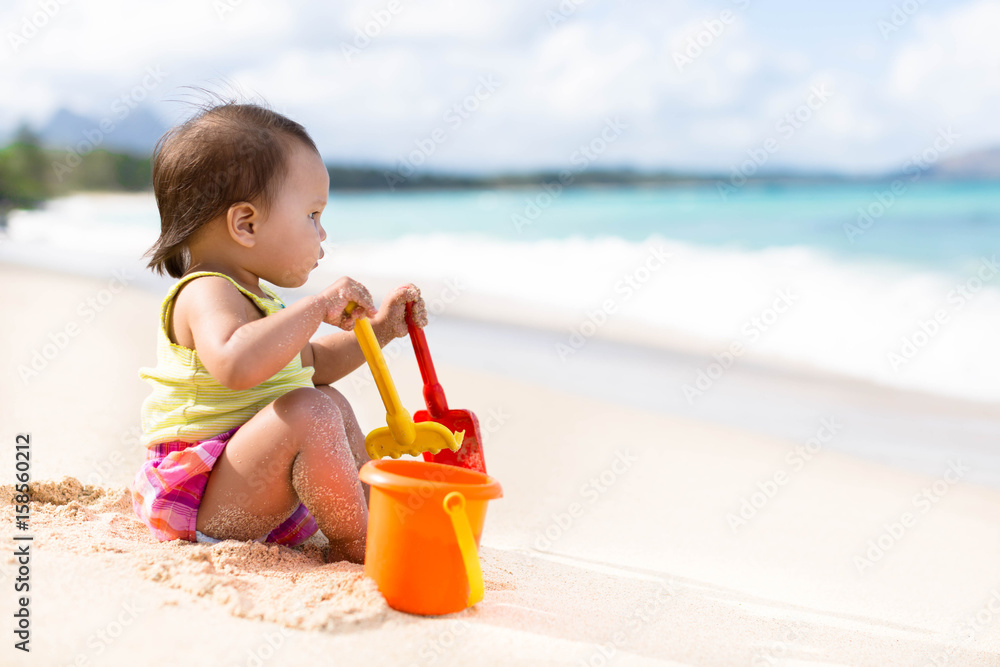 Child playing on sandy beach with a bucket and shovel Child playing on sandy beach with a bucket and shovel