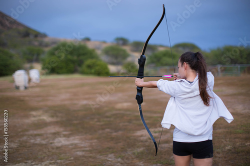 Athletic and athletic girl aiming a bow and arrow at an archery range.