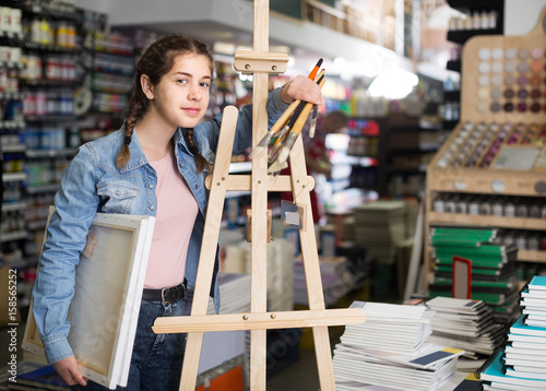 Teen girl holding supplies for painting in hands in art department
