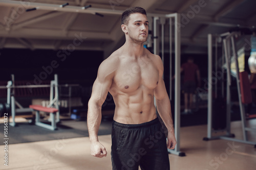 Sexy muscular man in gym working out. Strong male naked torso.