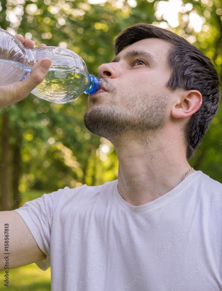 Young man is drinking water from bottle at sunny hot day. Young man is drinking water from bottle at sunny hot day.