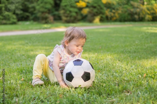 Little child is playing with football ball in park. © vchalup