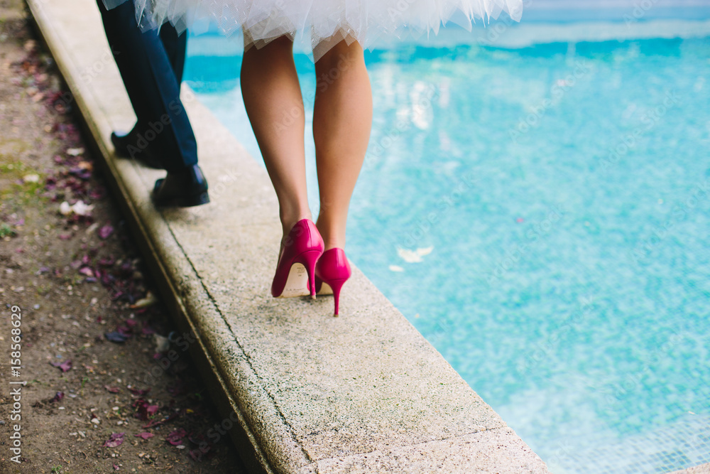 Mariés sur le bord d'une piscine talon rose bonbon et jambe de femme ...