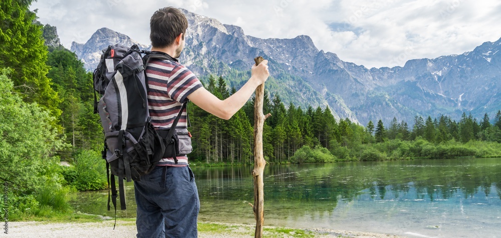 Hiking tourist from behind and lake near Alps in Almsee in Austria. Panoramic photo. Hiking tourist from behind and lake near Alps in Almsee in Austria. Panoramic photo.