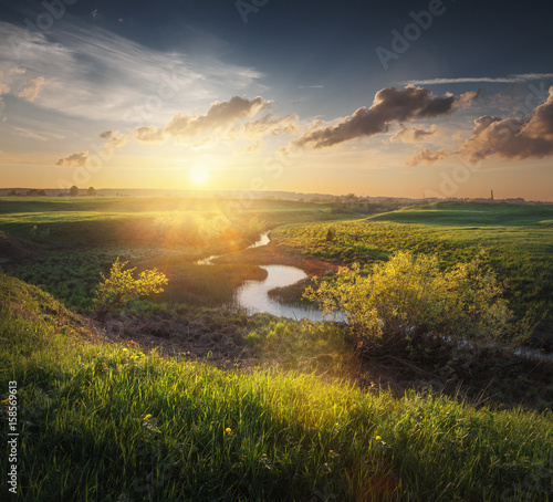 there is a small stream among spring fields