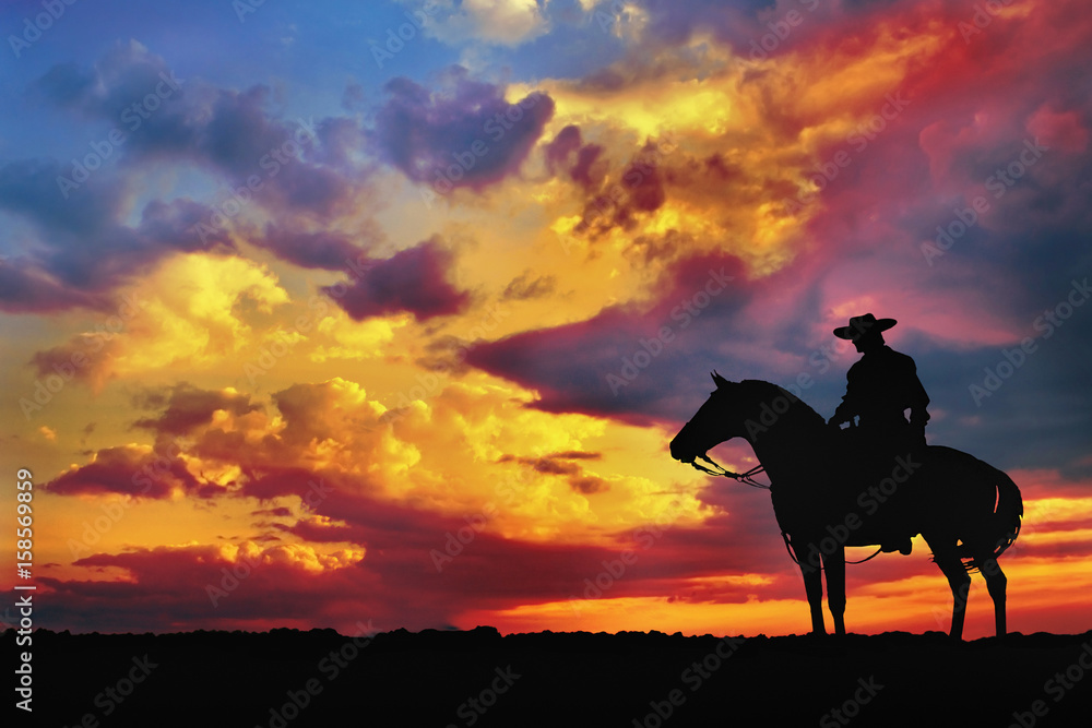 Naklejka premium sylwetka kowboja na koniu z pochmurnego nieba wieczorem