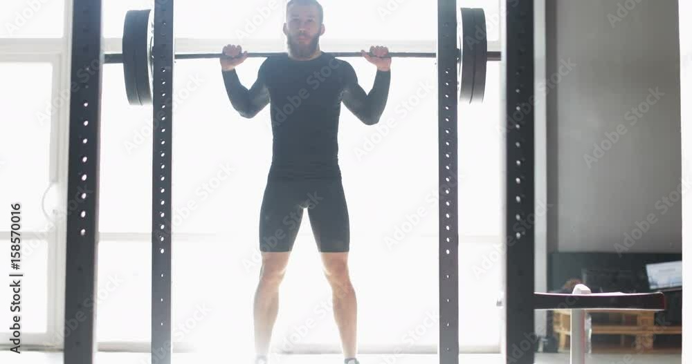 Young Man Exercising Doing Weighted Squats On Smith Machine During Workout Training At Gym Male Athlete Fitness Young Man Exercising Doing Weighted Squats On Smith Machine During Workout Training At Gym Male Athlete Fitness