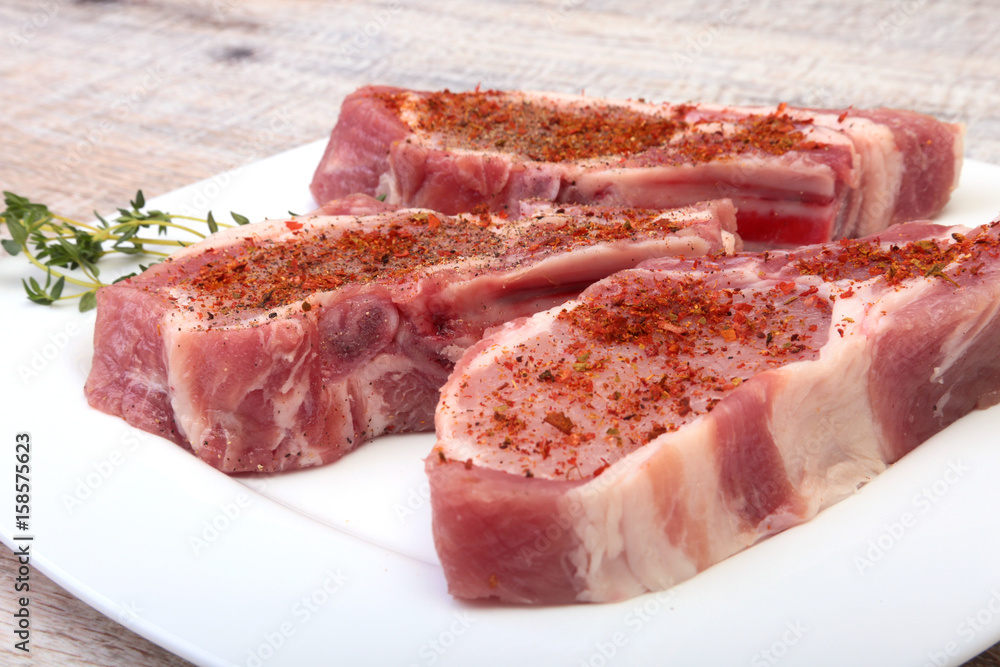 Raw pork chops, spices and rosemary on cutting board. Ready for cooking.