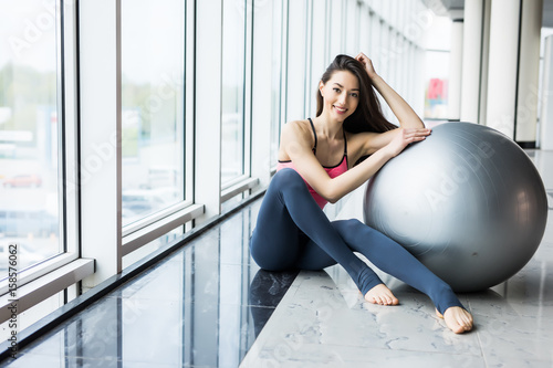 Woman working out with exercise ball in gym. Pilates woman doing exercises in the gym workout room with fitness ball. photo