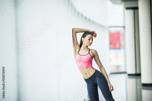 Fitness athlete sports woman relaxing after workout standing near on window