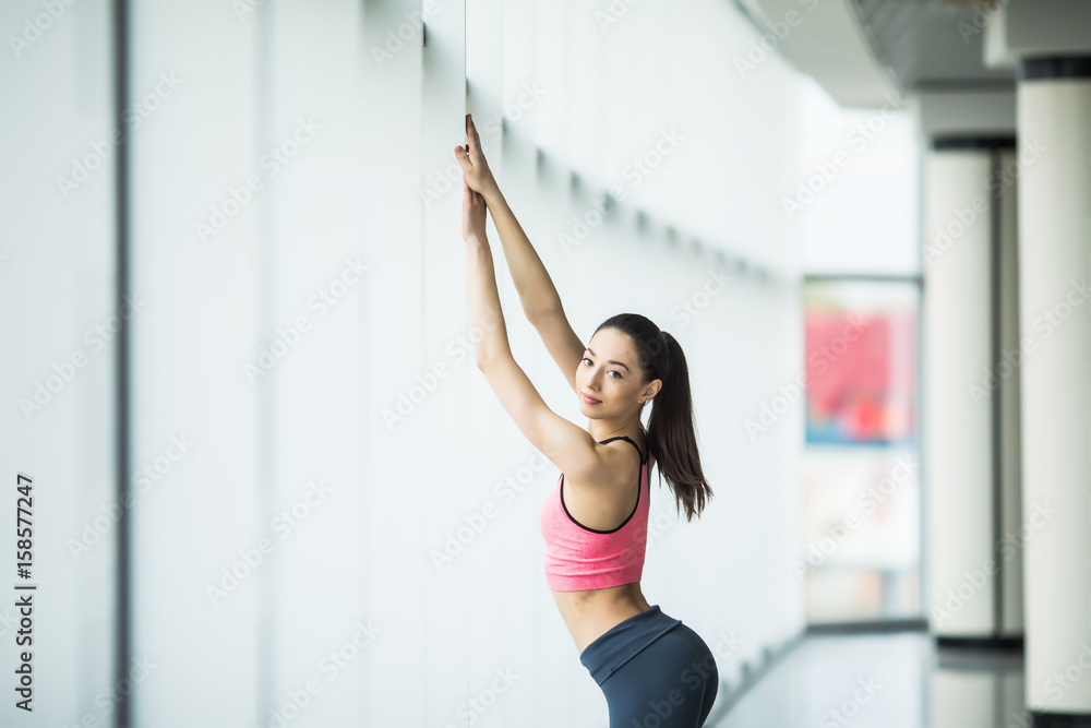 Young beautiful young woman in sportswear standing in front of window at gym Young beautiful young woman in sportswear standing in front of window at gym